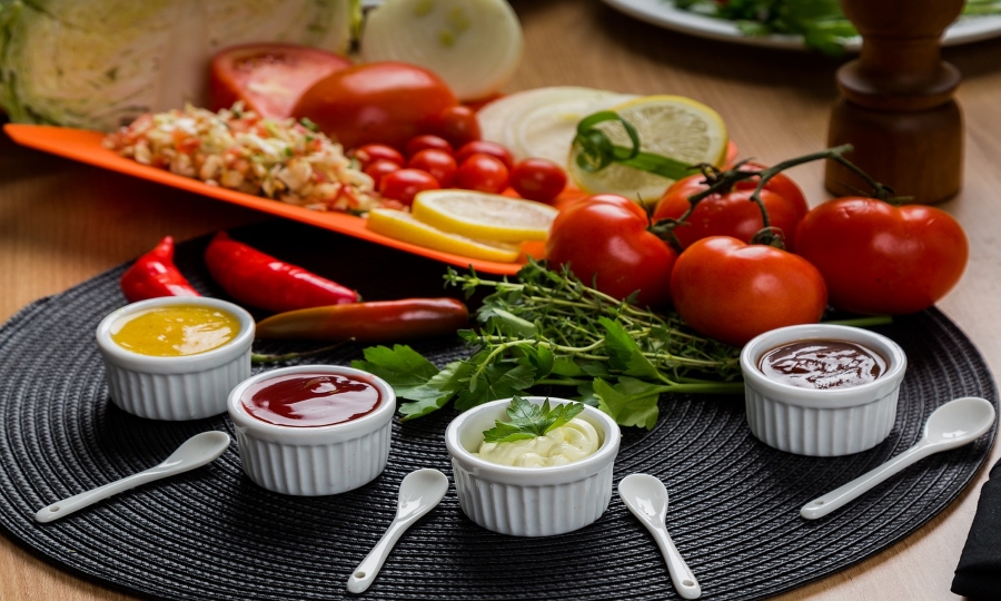 Zdjęcie przedstawia 4 miseczki z dipami, świeże pomidory i popryczki.