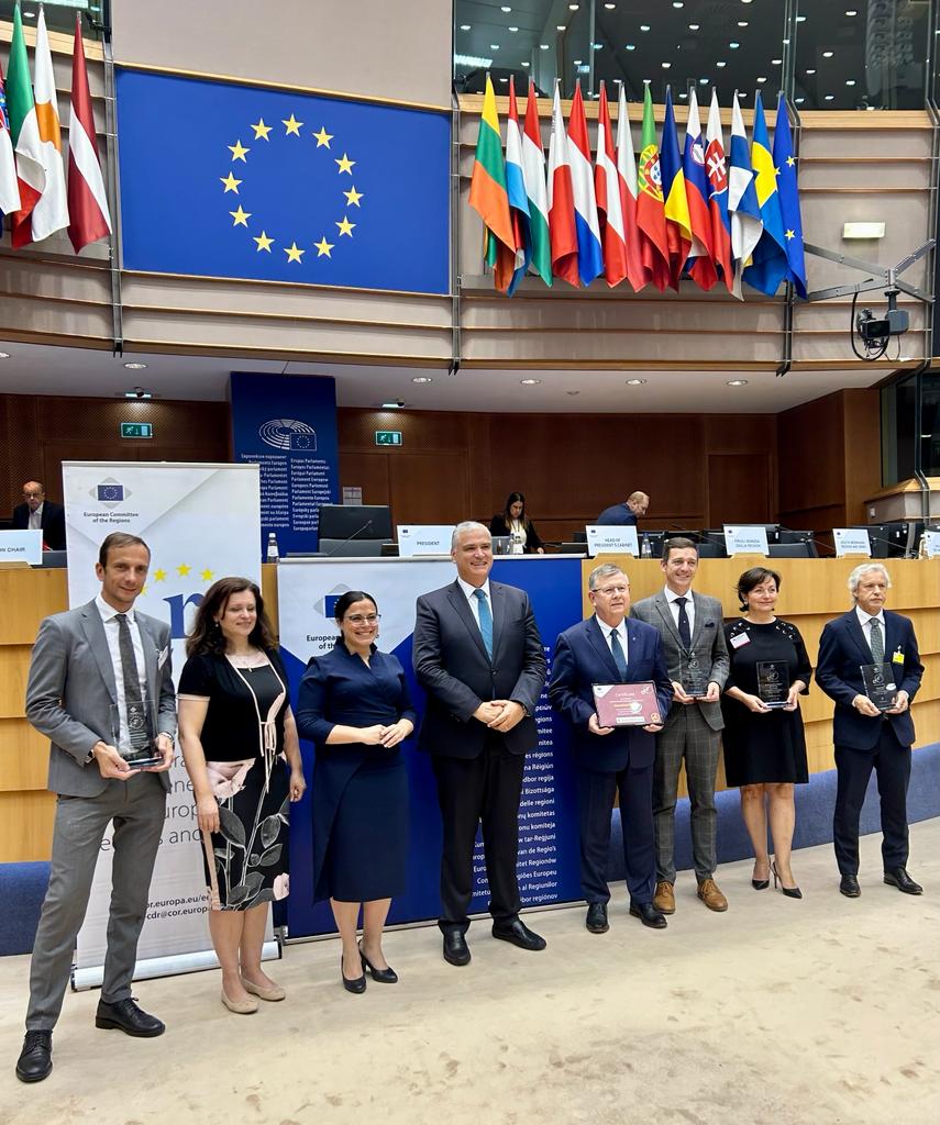 Ludzie elegancko ubrani trzymający nagrody. W tle sala Parlamentu Europejskiego