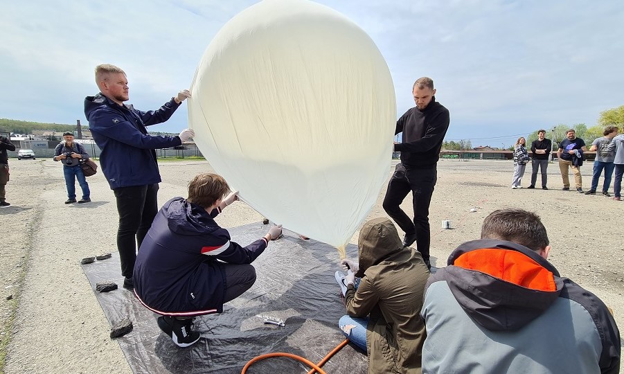 Sonda przed startem- pompowane powietrze do balonu. Mężczyźni podtrzymujący sondę przed startem